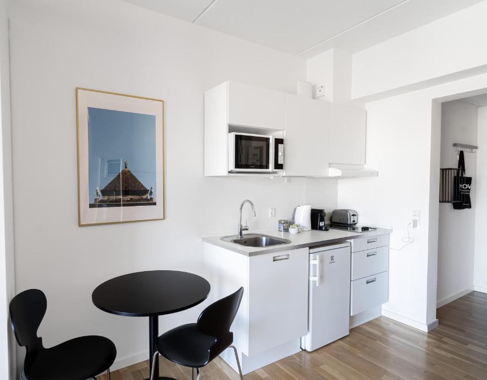 a white kitchen with black chairs and a sink at Cool studio in the South Harbour in Copenhagen