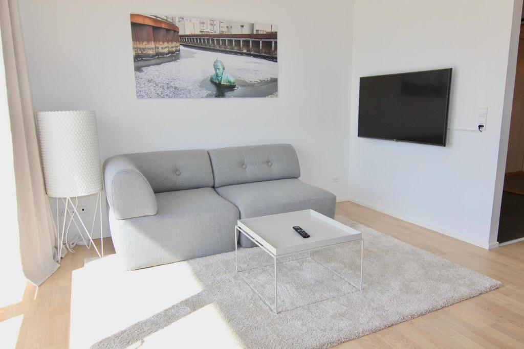 uma sala de estar com um sofá e uma televisão em Cool 1-bed w. private terrace em Odense