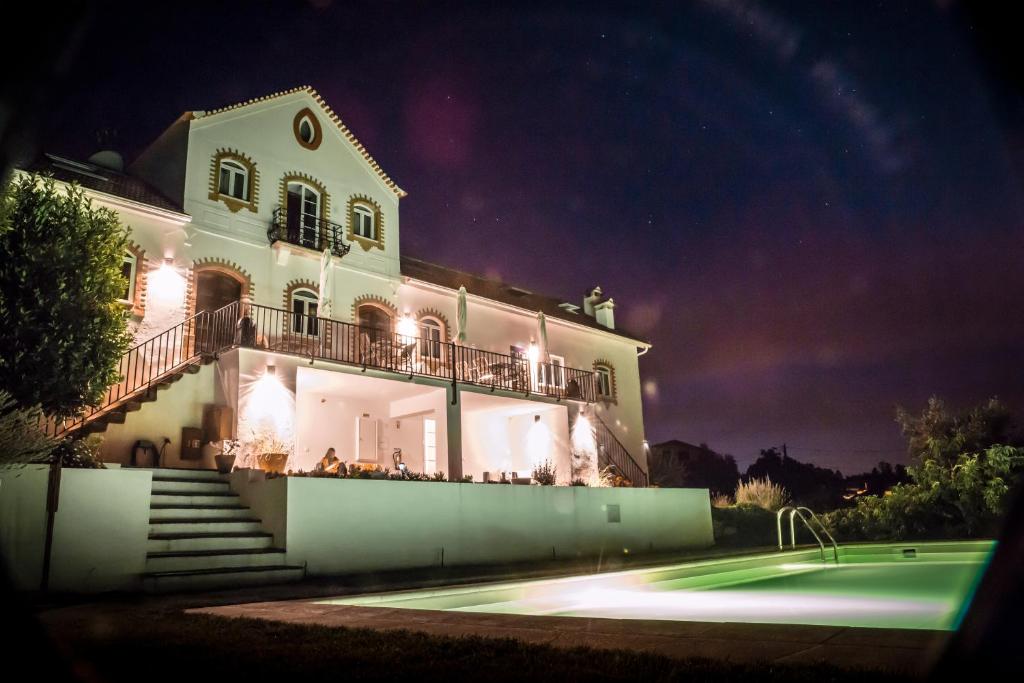 une grande maison blanche avec un court de tennis en face de celle-ci dans l'établissement Casa nas Serras, à Vila Nova de Poiares