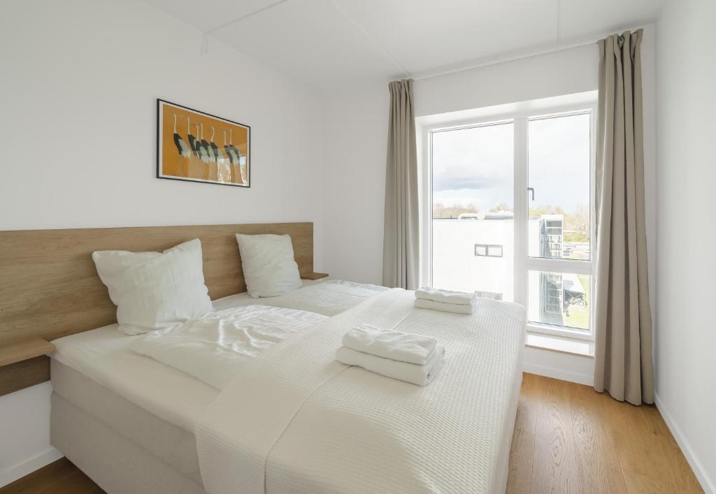 Top-class 1-bedroom apartment in Odense في أودنسه: غرفة نوم بيضاء مع سرير كبير عليها منشفتين