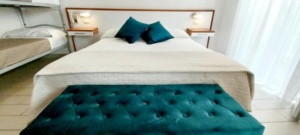 a bedroom with a large bed with blue pillows at Hotel Brotas in Rimini