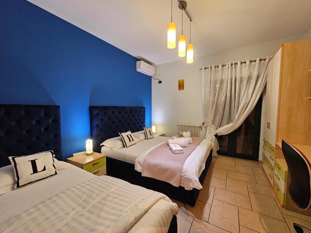two beds in a room with blue walls at Center Apartment Easy in Tirana