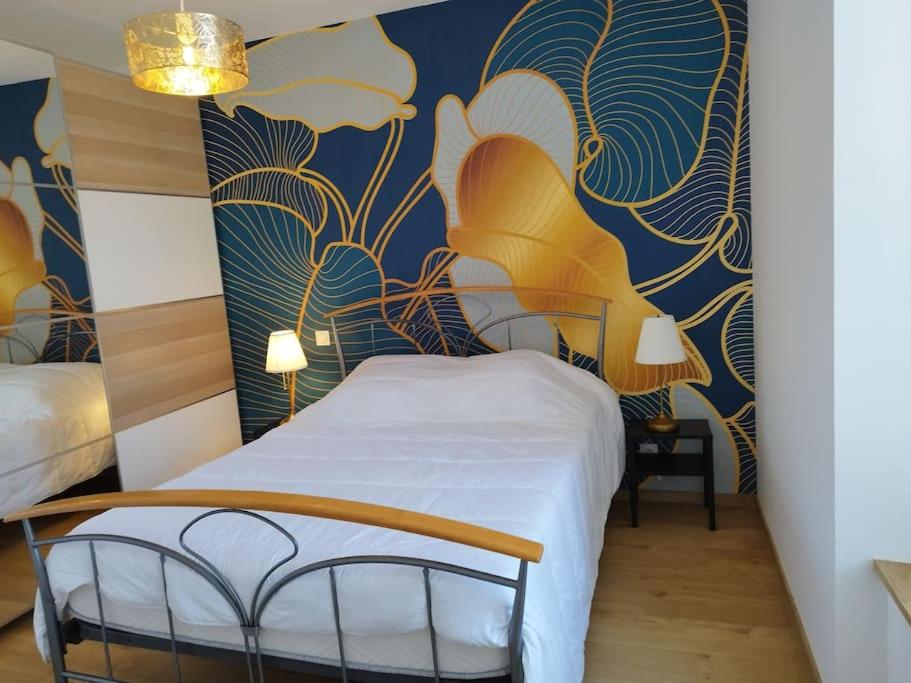 - une chambre avec un lit et un mur bleu et jaune dans l'établissement Grand T2 de charme, confort 3*, face aux Thermes., à La Bourboule