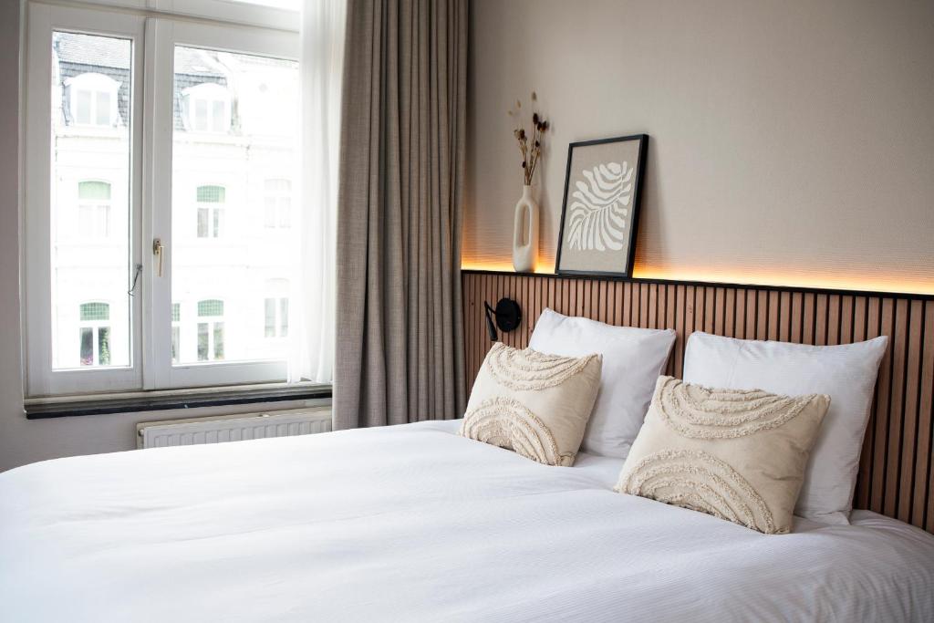 1 dormitorio con 1 cama grande con sábanas y almohadas blancas en Stadsherberg de Poshoorn en Maastricht