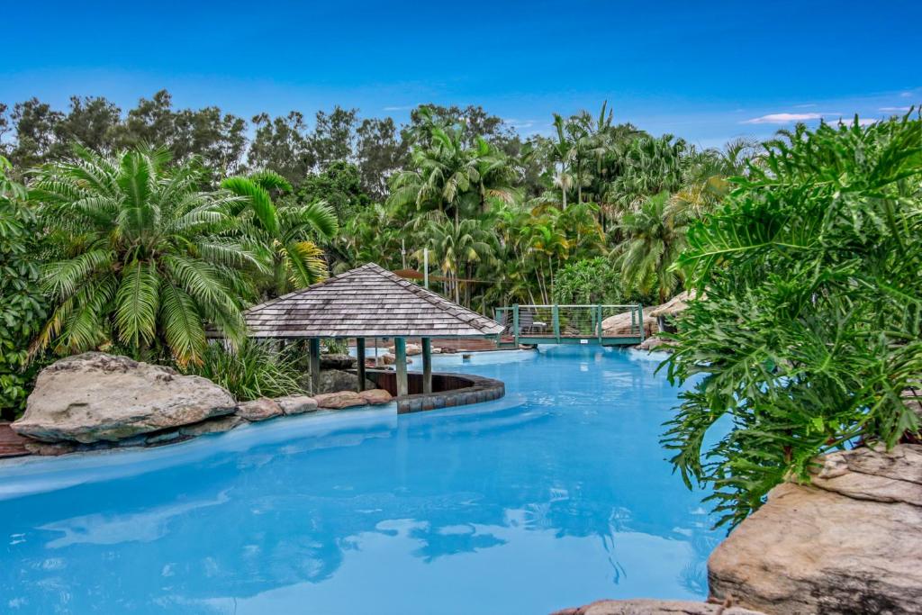 a resort pool with a gazebo and palm trees at Cuttlefish Cove in Coffs Harbour