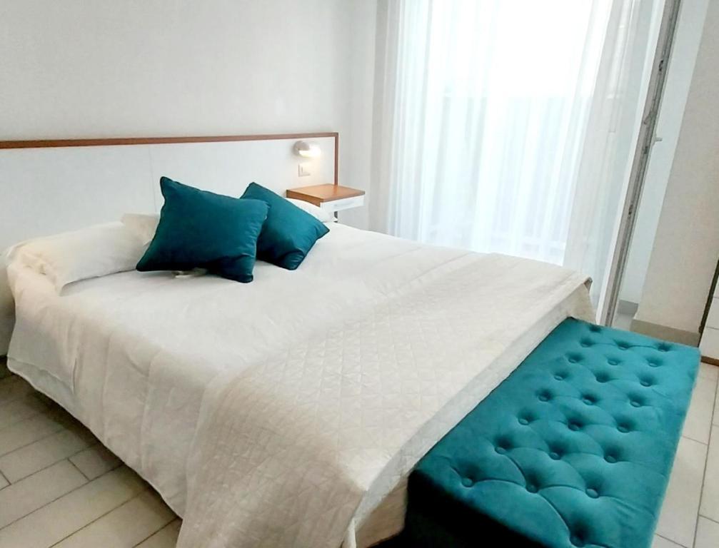 a bedroom with a large white bed with blue pillows at Hotel Brotas in Rimini