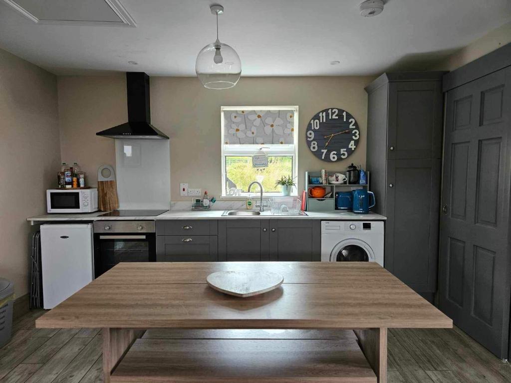 een keuken met een tafel en een klok aan de muur bij Croí Beag Luxury Studio in Dundalk