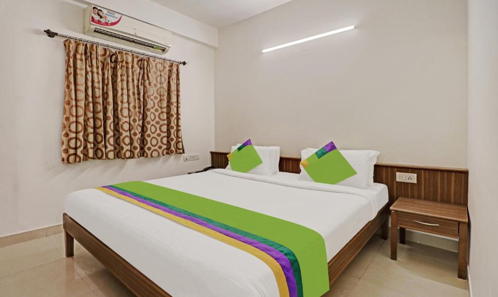 una camera da letto con un grande letto con lenzuola verdi e bianche di Treebo Trend Trinitywood a Bangalore
