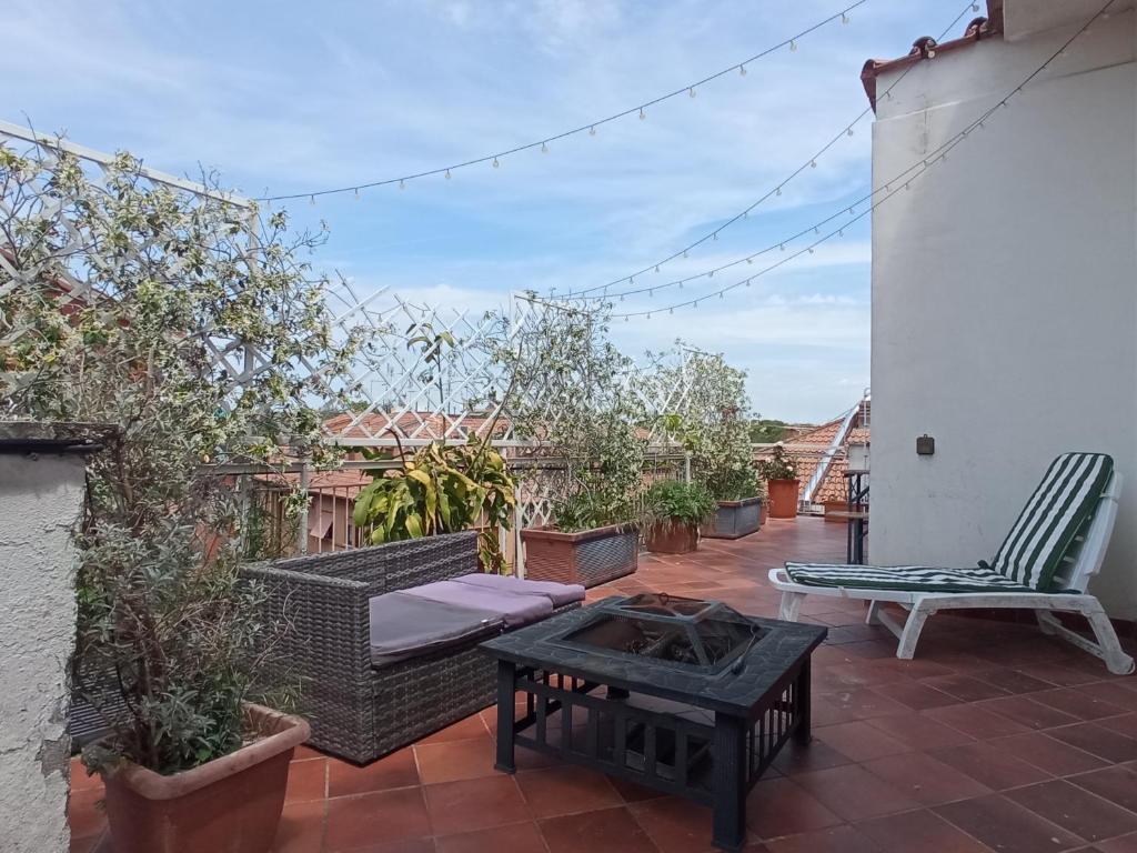 een patio met een bank en een tafel en stoelen bij Rooftop Appia antica, Attico silenzioso residenziale in Rome