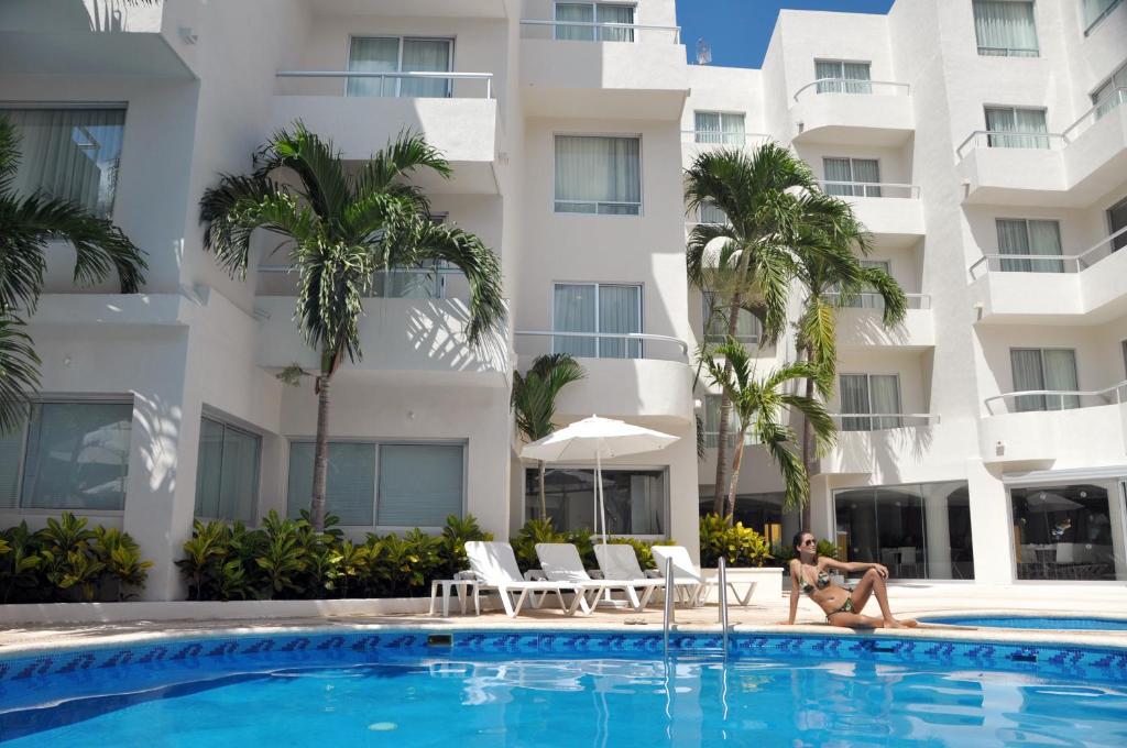 a person sitting in a pool in front of a building at Adhara Express in Cancún