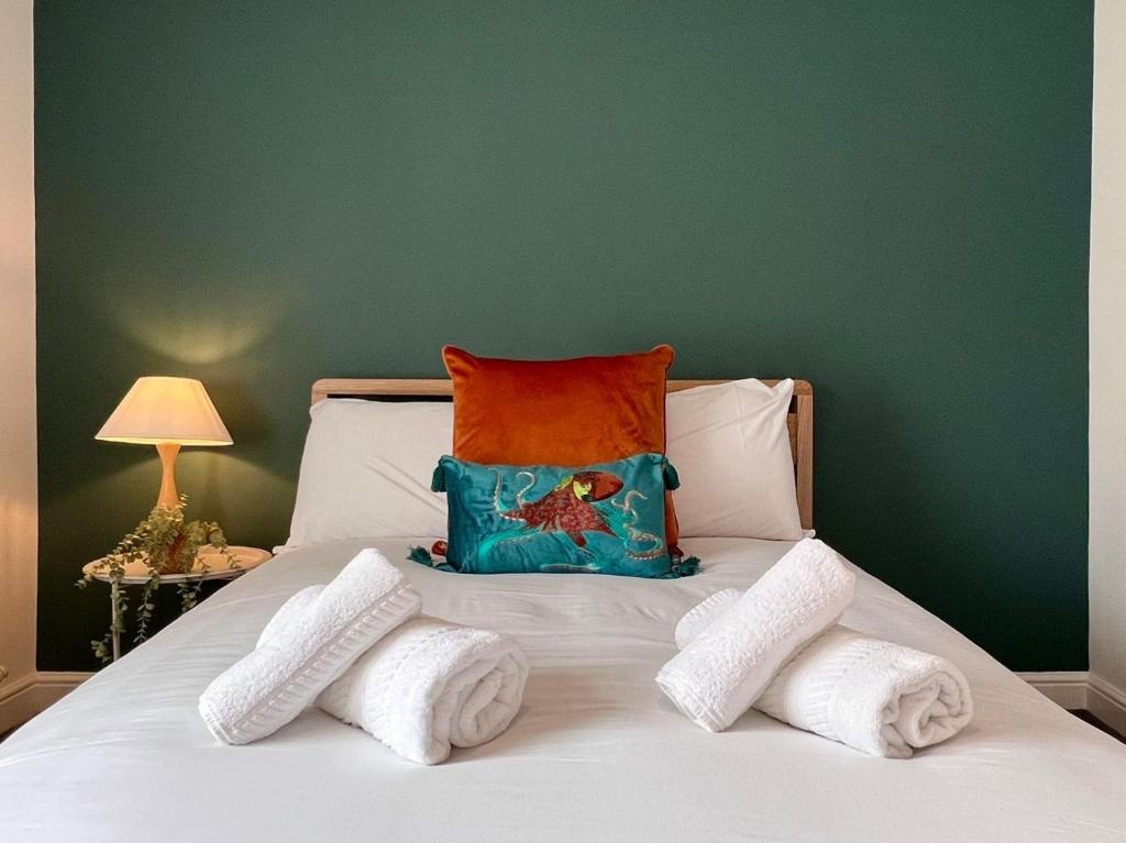 una cama con una pared verde y una almohada en ella en Quaint 2Bed House near Wigan Centre en Ince-in-Makerfield