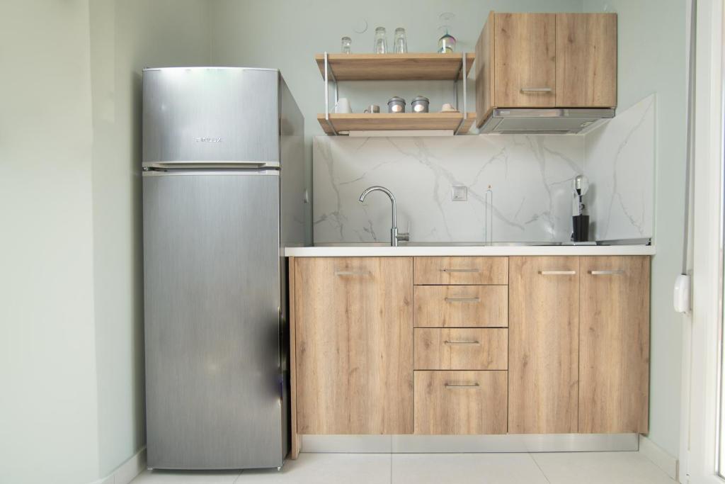 a kitchen with a stainless steel refrigerator and wooden cabinets at Olea Apartments Palioura Epanomi in Epanomi