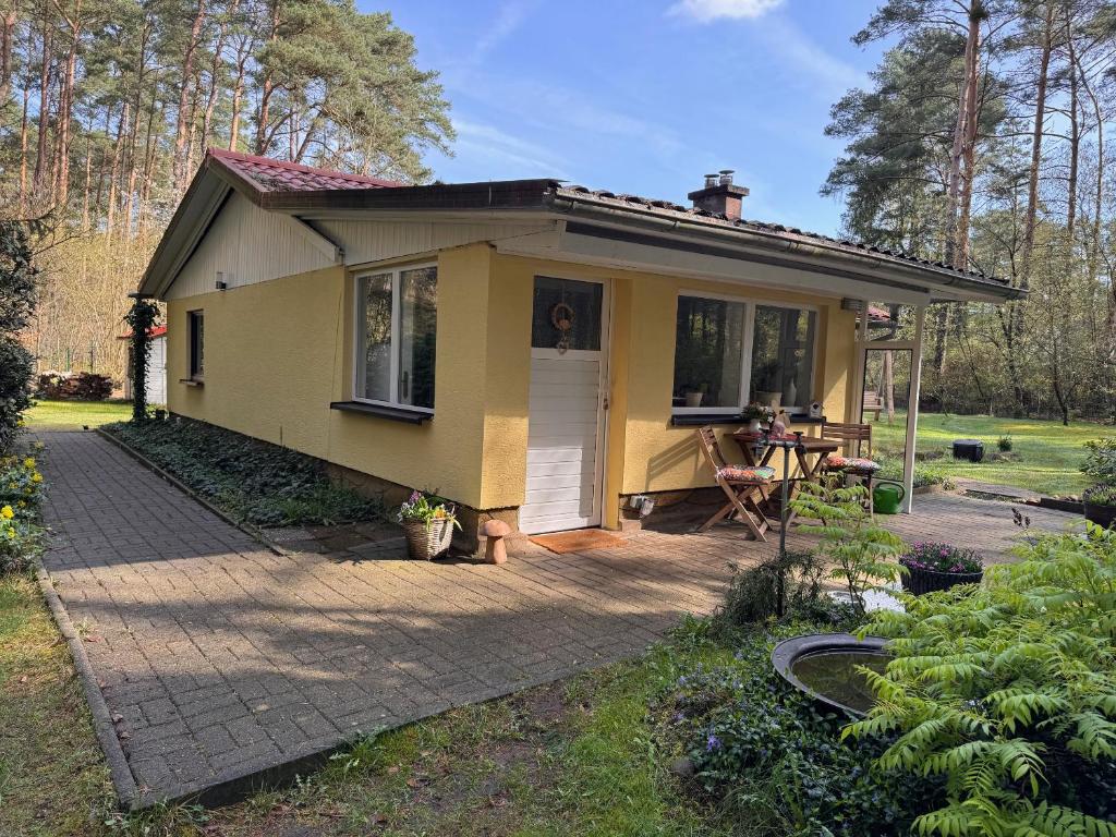 Borkwalde的住宿－Ferienhaus im Wald，一个小黄房子,设有露台