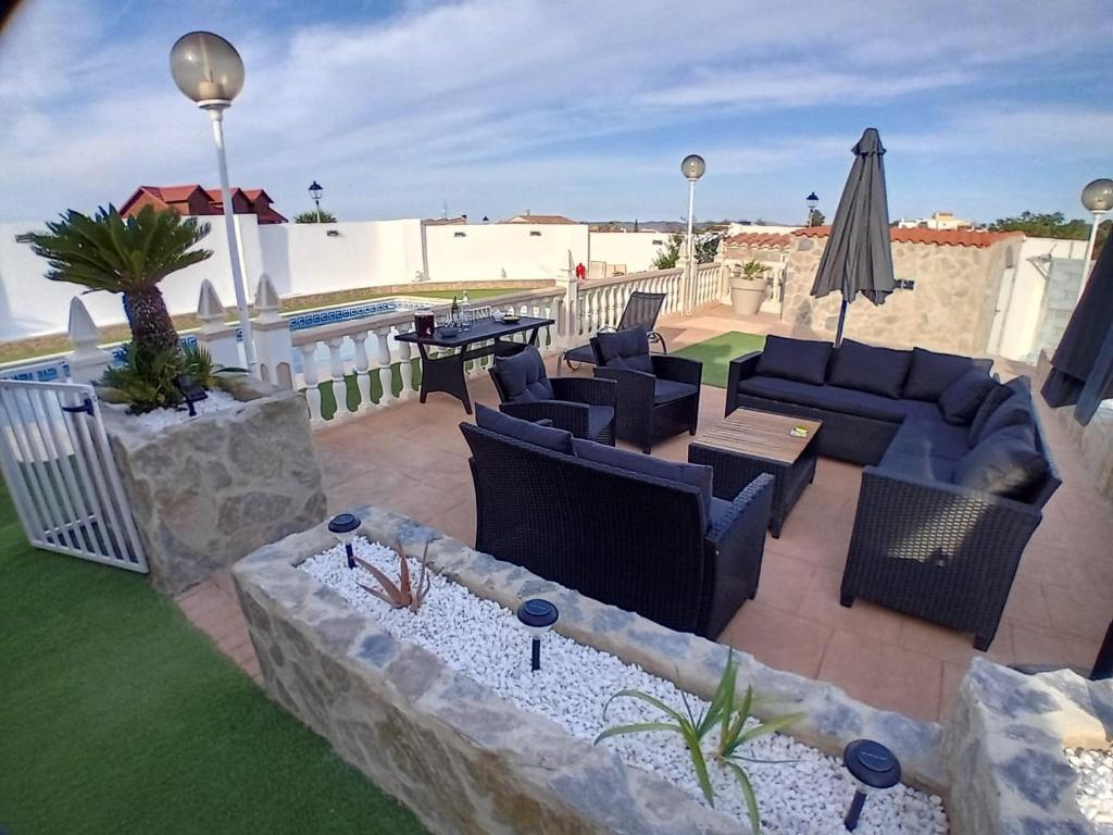 une terrasse avec des canapés, une table et un parasol dans l'établissement Casa de Verano con Piscina, à Montroy
