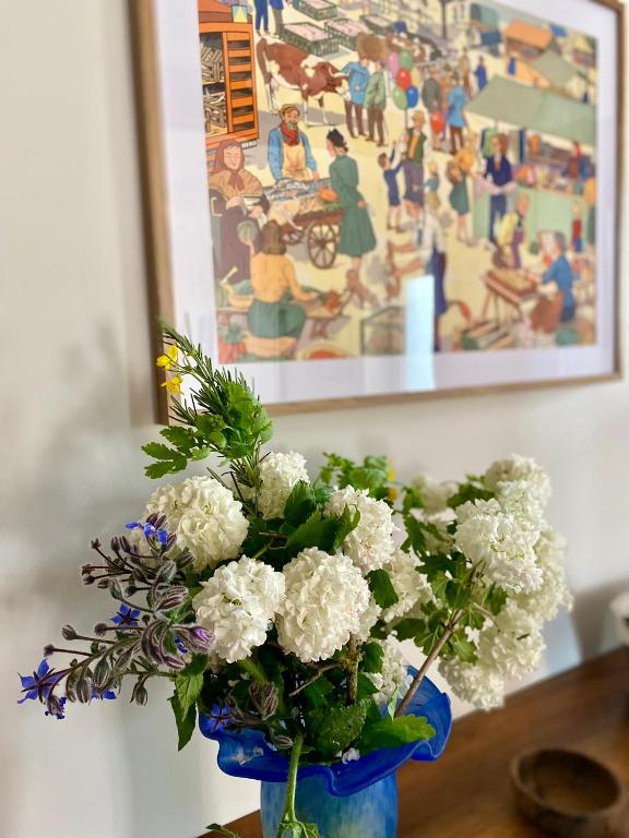 un vase bleu rempli de fleurs blanches sur une table dans l'établissement Gîte de la maison jaune - Comblanchien, à Comblanchien