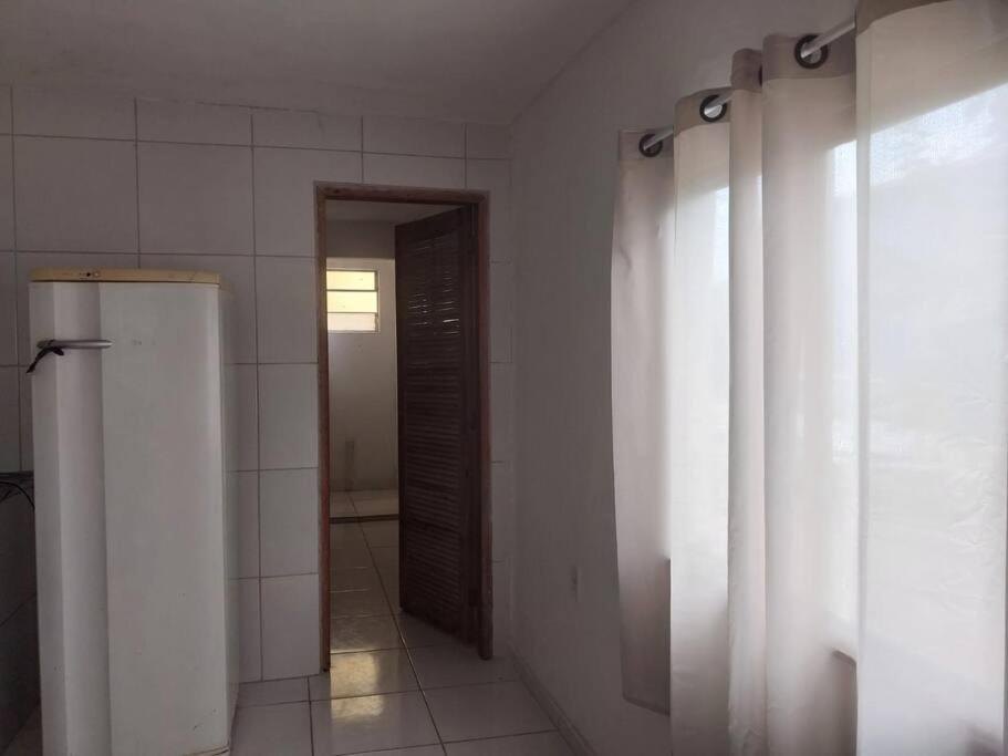 een badkamer met een koelkast en een deur naar een kamer bij kitnet Bela Vista in Maricá