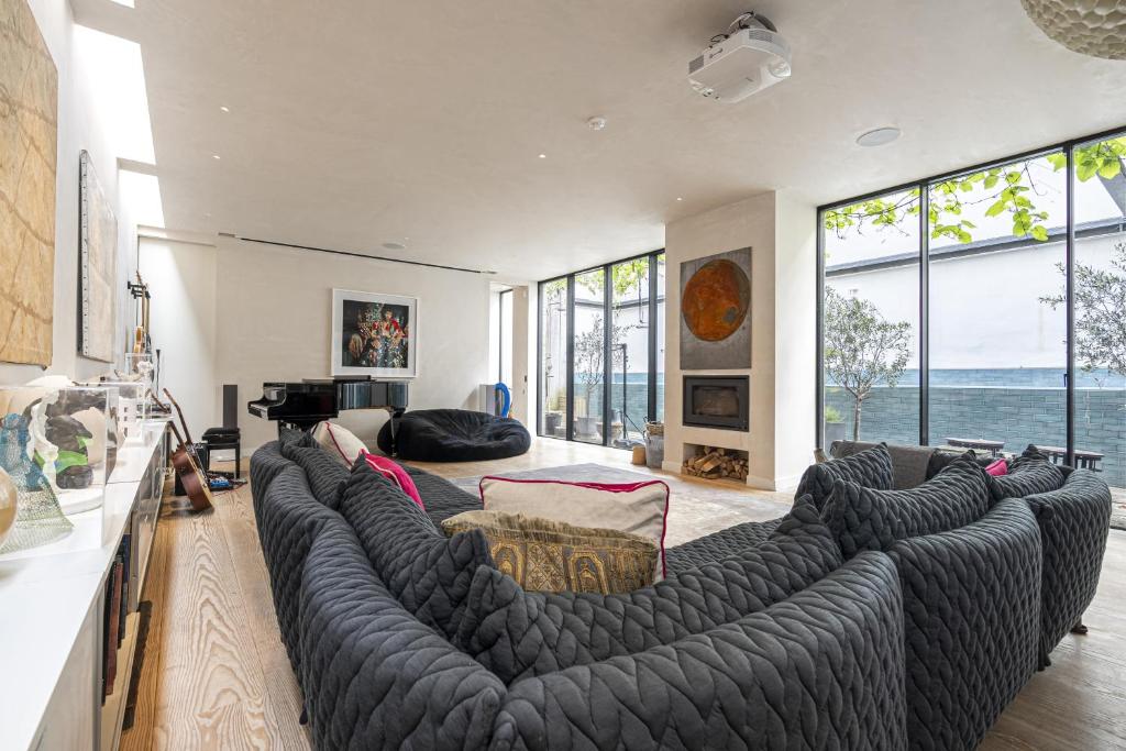 ein Wohnzimmer mit einem großen Sofa und einem großen Fenster in der Unterkunft JOIVY Architectural gem with pool and terrace in West London in London