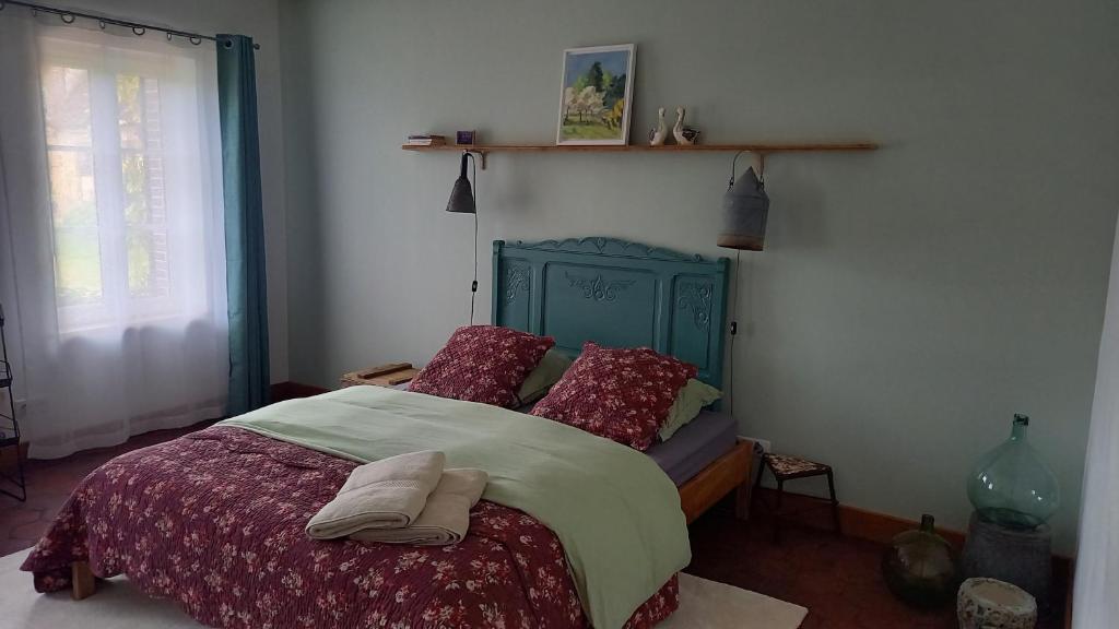 Schlafzimmer mit einem Bett mit einem grünen Kopfteil und roten Kissen in der Unterkunft Gîte des Hirondelles in La Noë