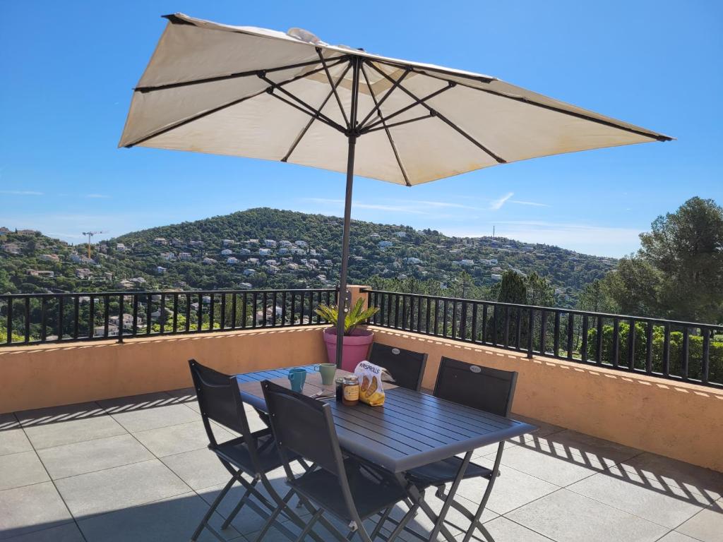 d'une table bleue, de chaises et d'un parasol sur le balcon. dans l'établissement Rooftop les Issambres, aux Issambres