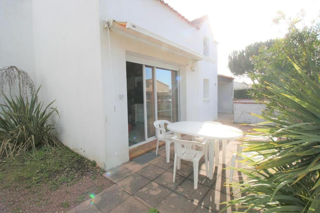 un patio avec une table et des chaises devant une maison dans l'établissement Studio, secteur le Phare, à La Tranche-sur-Mer
