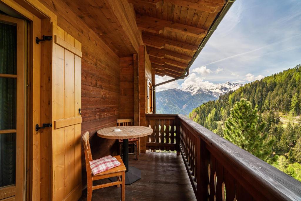 balcón con mesa y vistas a la montaña en Ferienwohnung Innerkaserbach en Motini al Rio