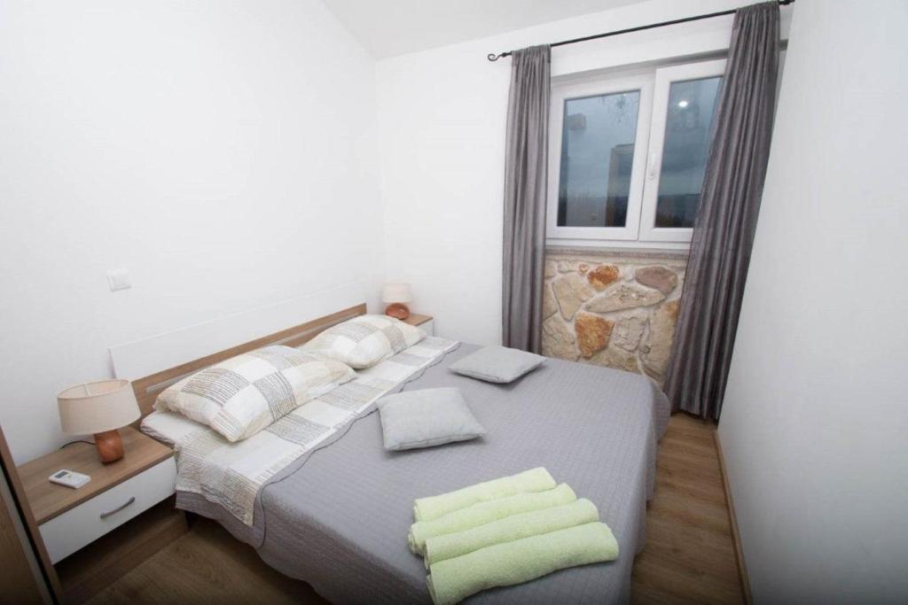 ein Schlafzimmer mit einem Bett mit Kissen und einem Fenster in der Unterkunft Moderne Wohnung in Privlaka mit Terrasse, Garten und Grill in Privlaka