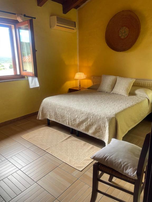 sypialnia z łóżkiem, krzesłem i oknem w obiekcie Affitti brevi Tzia Licca w mieście Teulada