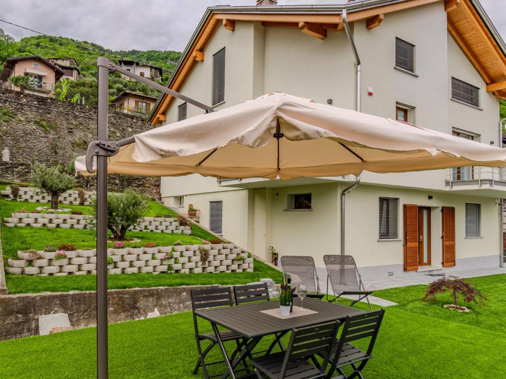 ein Tisch mit Sonnenschirm vor einem Haus in der Unterkunft Apartment Syria by Interhome in Domaso