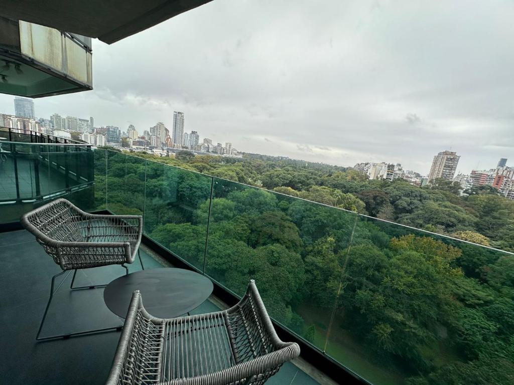 a balcony with two chairs and a table and a city at Mansión Botánico Luxury Buenos Aires in Buenos Aires