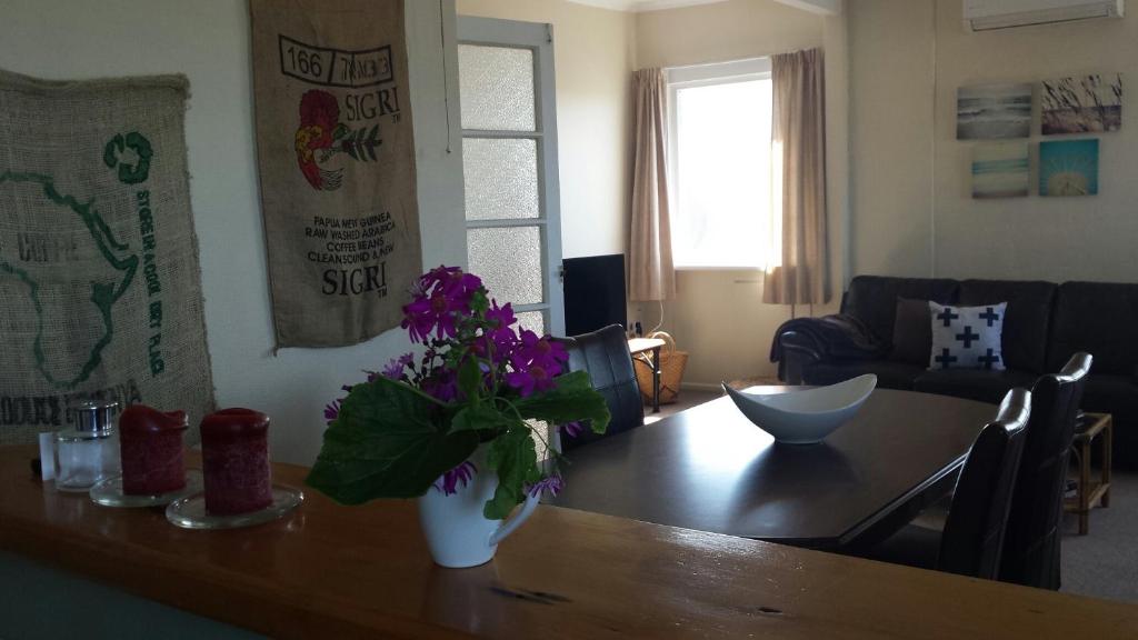 una sala de estar con una mesa de madera con flores púrpuras. en Coastal Accommodation en Oamaru