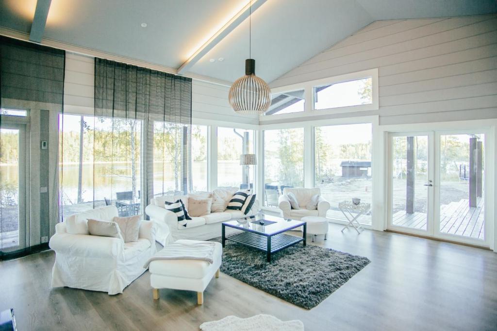 a living room with white furniture and large windows at SleepWell Villa Hartola in Kirkkola