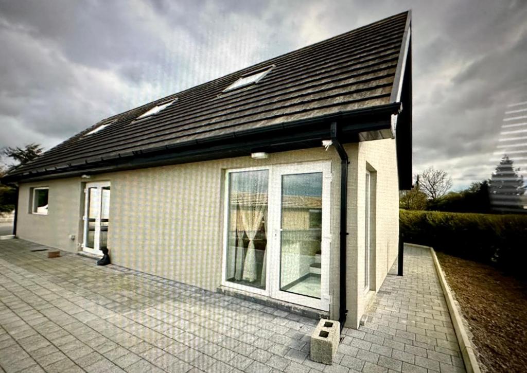 une petite maison blanche avec un toit noir dans l'établissement Country Haven Comfy & Sleek Apartment, à Kildare