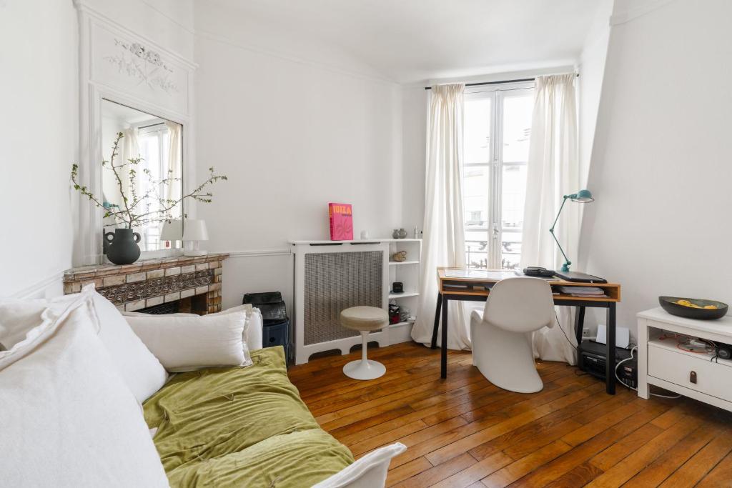 Cette chambre blanche comprend un lit, un bureau et une table. dans l'établissement Luxe appartement Parisien, à Paris