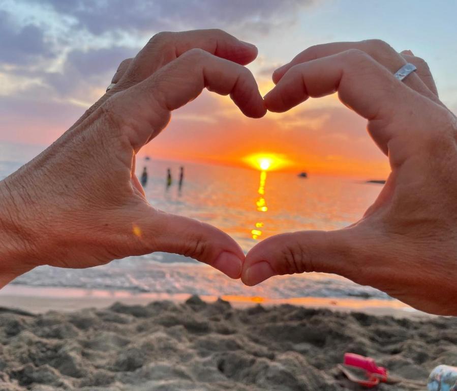 un par de manos formando un corazón en la playa en Martino10 en Carloforte