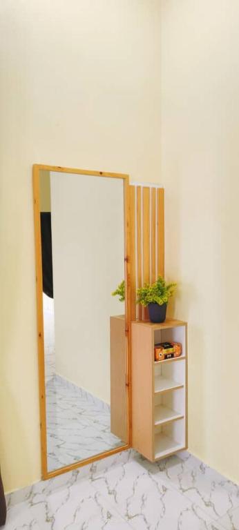 a mirror in a room with a cabinet and a plant at Teratak Mek Siti Homestay in Kota Bharu
