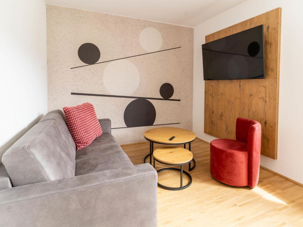 a living room with a gray couch and a red chair at Apartment be balance by Interhome in Mieming