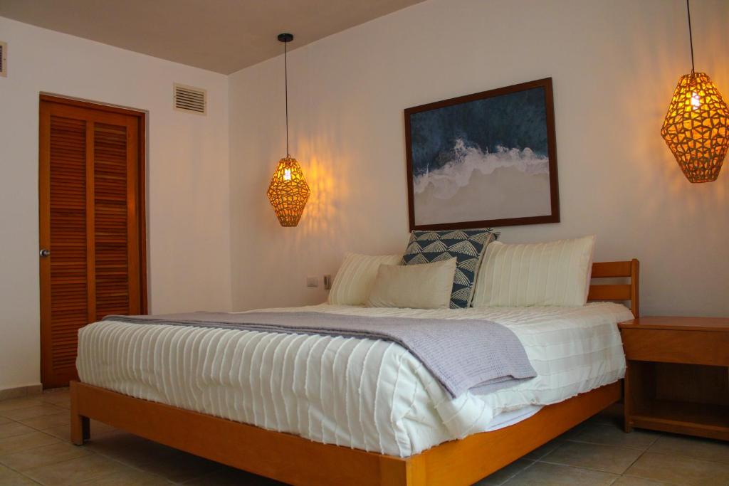 Villas Mayaluum Cozumel في كوزوميل: غرفة نوم بسرير كبير وعليها مصباحين