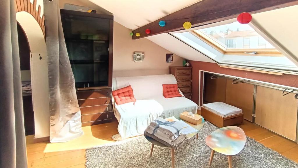 Cette petite chambre mansardée comprend un lit et une fenêtre. dans l'établissement Coquet 2 pièces sous les toits, à Fresnes