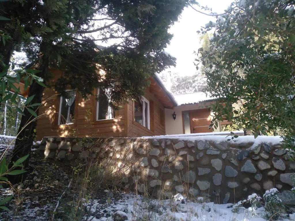 a wooden house with a stone wall in front of it at Cabañas del Gutiérrez in San Carlos de Bariloche