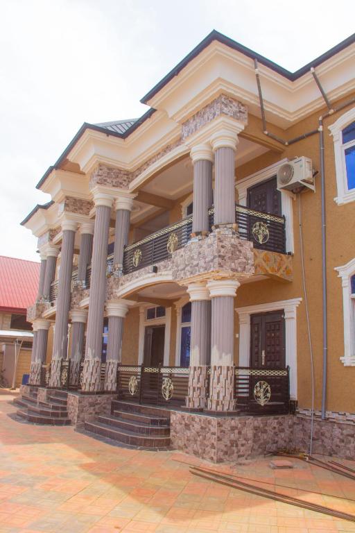 a large building with columns and a balcony at Maakyere Apartments in Kintampo
