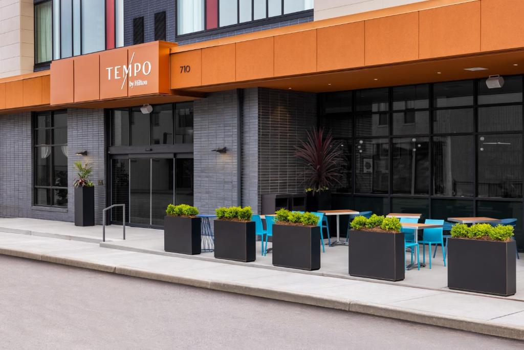 a building with tables and potted plants in front of it at Tempo By Hilton Louisville Downtown Nulu in Louisville