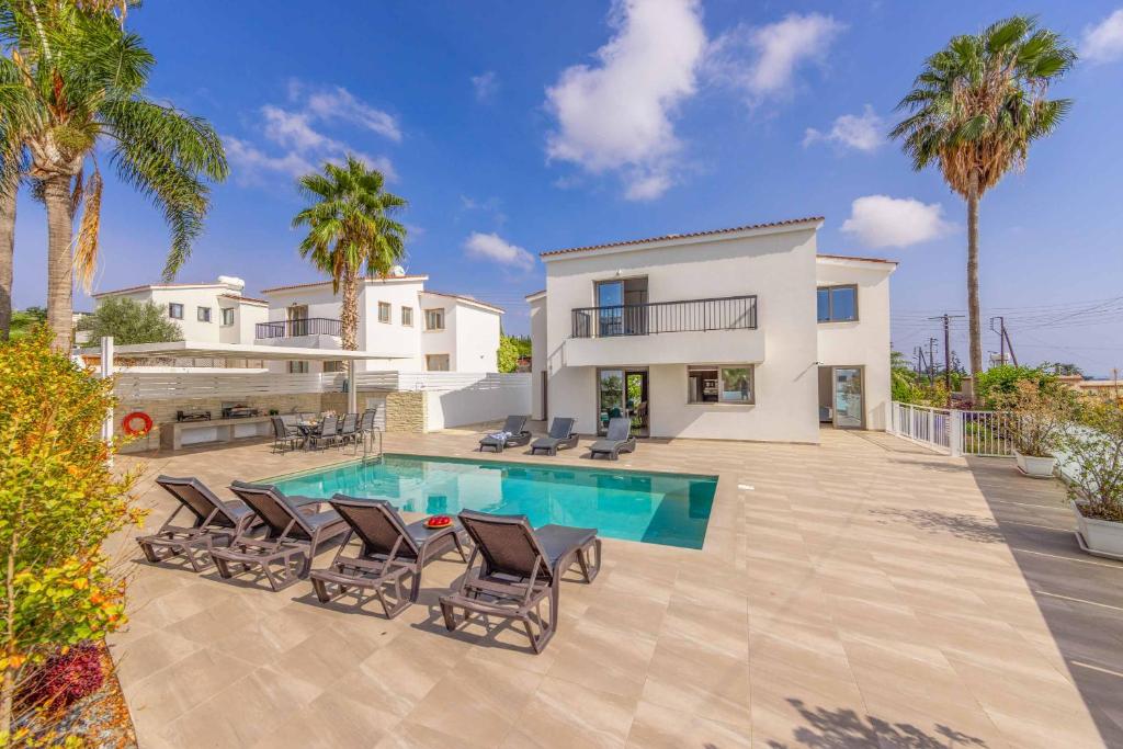 a villa with a swimming pool and palm trees at Villa Christina Coral in Peyia