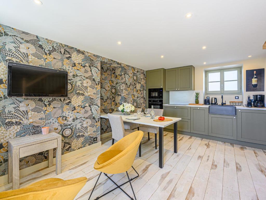 a kitchen with a table and a tv on a wall at Holiday Home Colary by Interhome in Carnac