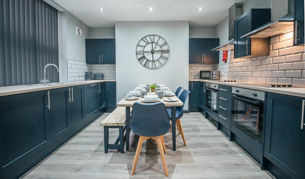 a kitchen with blue cabinets and a table and chairs at The Shaftesbury House - 8 Bedroom House in Stockton-on-Tees