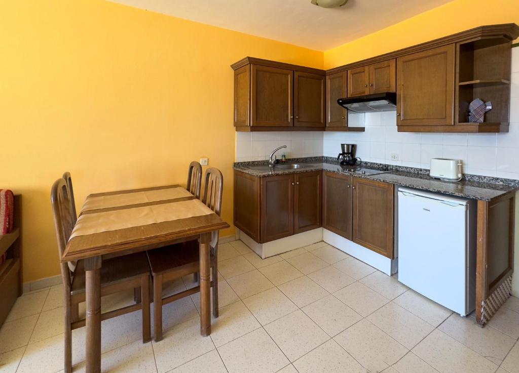 a kitchen with wooden cabinets and a table and a refrigerator at Complejo Las Tres Palmeras in Valle Gran Rey