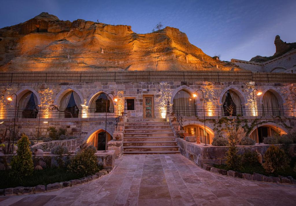 a stone building with lights in front of a mountain at Sur Cave Hotel in Ürgüp