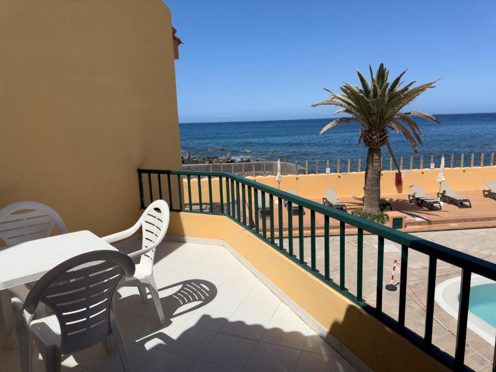 a balcony with a table and chairs and the beach at Complejo Las Tres Palmeras in Valle Gran Rey