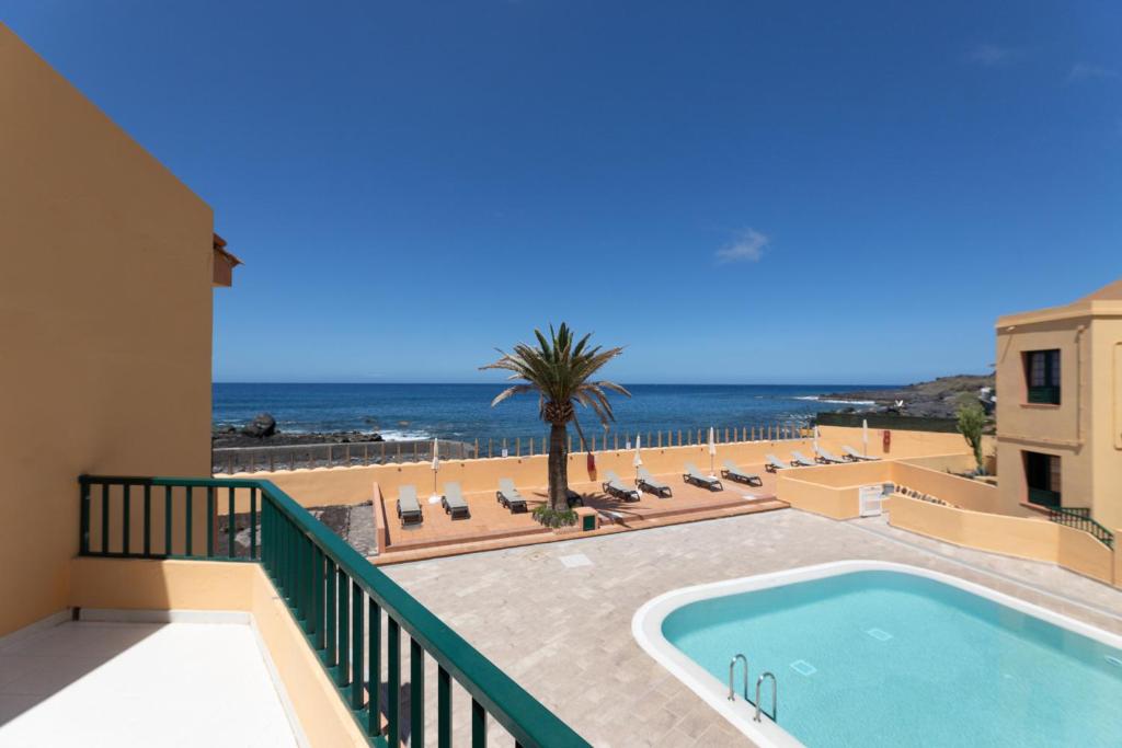 a balcony with a swimming pool and the ocean at Complejo Las Tres Palmeras in Valle Gran Rey