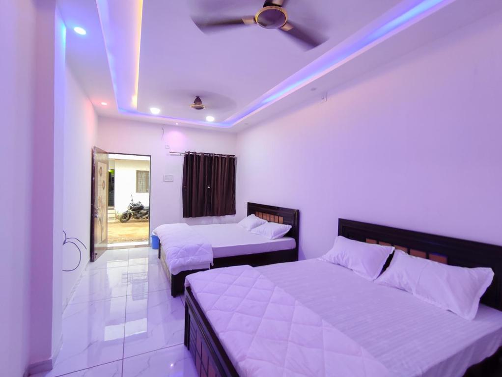 a bedroom with two beds and a ceiling fan at Family Homestay in Garudeshwar
