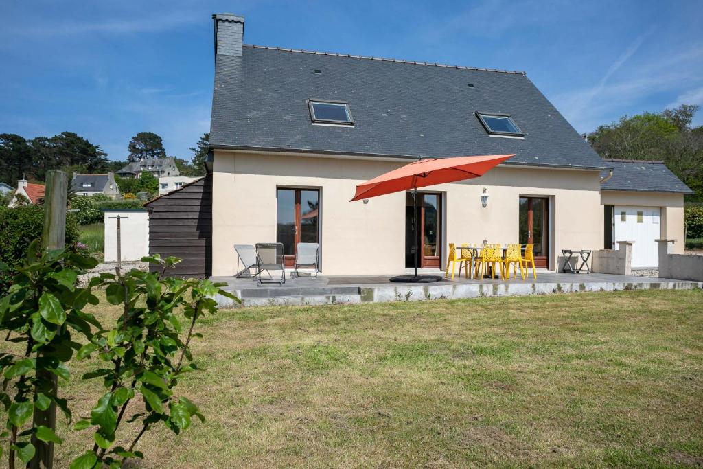 Cette maison dispose d'une terrasse avec un parasol rouge. dans l'établissement Le Clos Penvern, à Pleumeur-Bodou